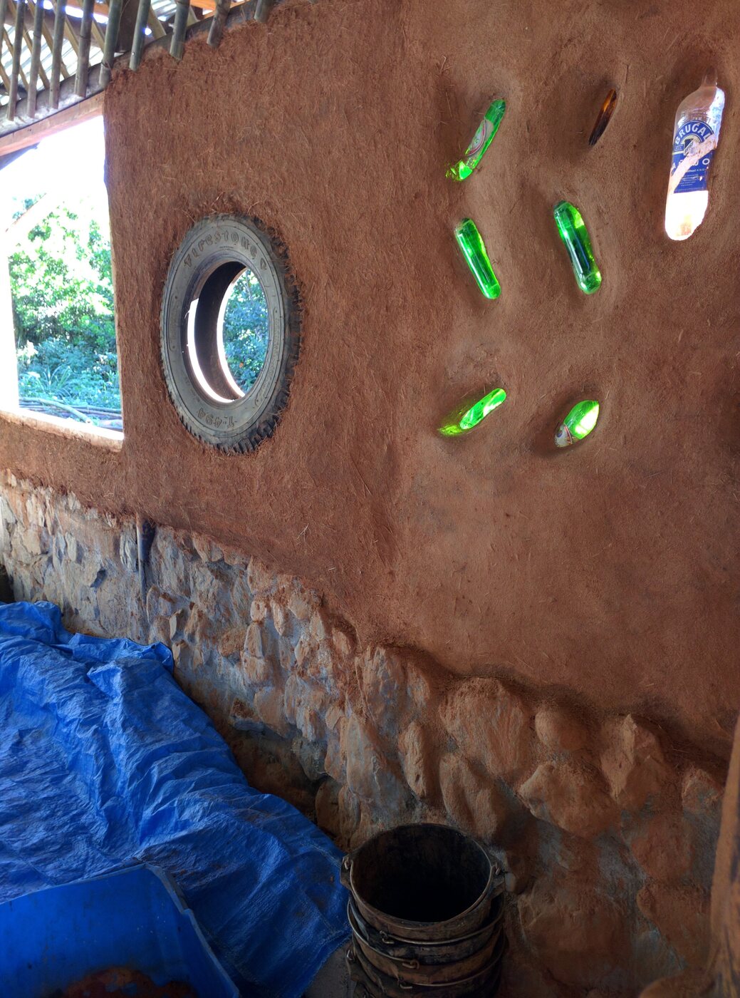 Botellas insertándose en la pared antes de terminar de tapar con barro